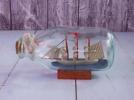 boat in  bottle on wood table for travel or transport concept photo