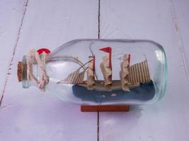 boat in  bottle on wood table for travel or transport concept photo