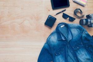 Top view of clothing and diverse personal accessory on the wooden table background. photo