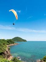 hermoso paisaje marino con parapente volando en el cielo azul. foto