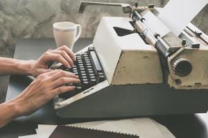 Close up of Male hands typing on typewriter on the desk. Vintage tone photo