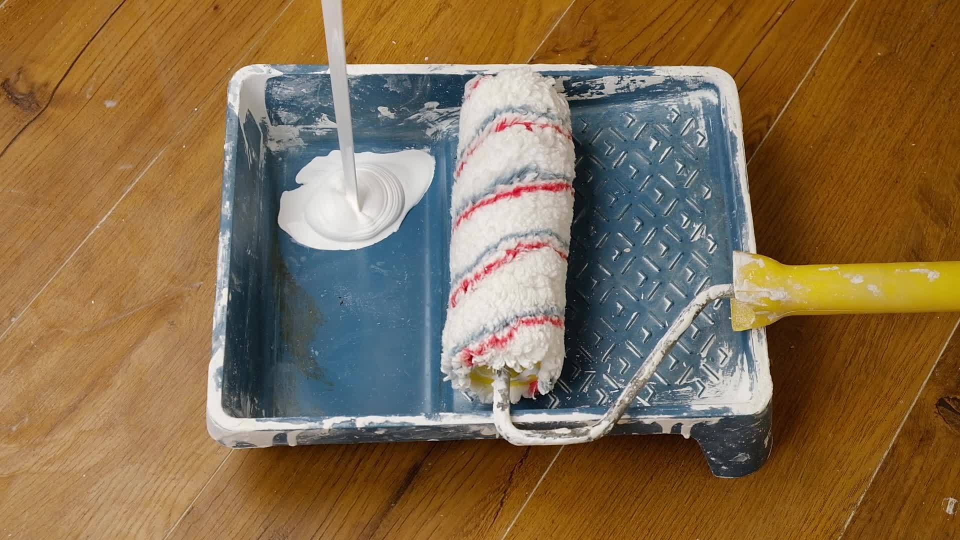 wall painting preparation, pouring white paint into a tray. High