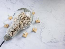 bombilla y cubo de madera del alfabeto en mármol blanco para idea o concepto de pensamiento foto