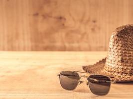 Sunglasses and hat on the wooden table photo