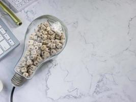 light bulb and alphabet wood cube on white marble for idea or think concept photo