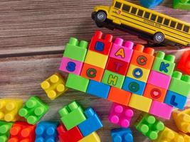 Toy brick and school bus on wood table photo