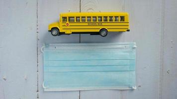 school bus and mask on wood table for education  or medical  concept photo