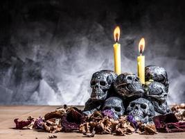 Skulls with candle burning and dried flowers on dark background. photo