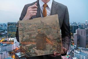 Double exposed of Businessman holding a shopping bag with cityscape at night. photo