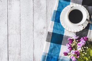 Top view of Coffee cup with flowers and tablecloth on wooden table background, Free space for text photo
