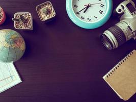 Top view of camera with cactus,map,globe,clock and notebook on the office desk.Vintage tone photo