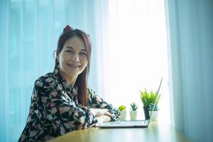 Woman working on laptop at home while talking on phone. photo