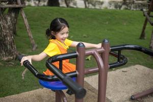 Asian happy girl with orange dress is playing in the playground. photo