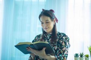 concepto de estudio bíblico. mujer asiática lee la biblia en casa. foto