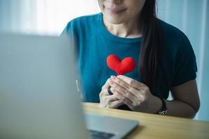 Asian Woman showing red heart on computer. Dating Online concept. photo