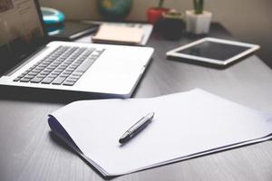 papeles en blanco con bolígrafo, tableta y computadora portátil en el escritorio. foto