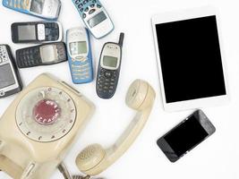 Tablet with smart phone and old phones on white background photo