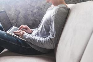 Casual young man using laptop on sofa at home. photo