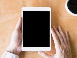 Top view of  male hands using tablet with coffee cup on wooden table. photo