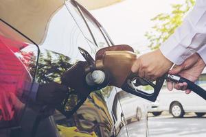 hombre poniendo gasolina en su coche en una gasolinera de bomba foto