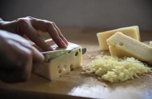 mujer preparando queso para cocinar usando rallador de queso en la cocina - gente haciendo comida con concepto de queso foto