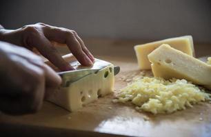 Woman preparing cheese for cook using cheese grater in the kitchen - people making food with cheese concept photo