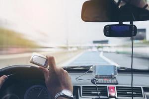 Man driving car using navigator and holding electronic toll collection system device photo