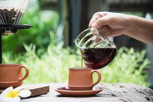 hombre haciendo goteo de café recién hecho en una cafetería antigua con fondo verde de la naturaleza - gente con café recién hecho en el concepto de naturaleza foto