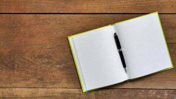 Top view workspace with blank notebook and pen on wooden table background . photo