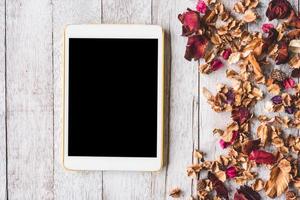 Top view of  Tablet with Dried flowers on wooden table background. photo