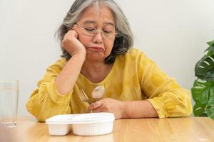 infeliz anorexia anciana asiática y dice no a las comidas preparadas, ancianos solos en casa y comida aburrida y sin apetito foto