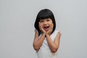 retrato de niña asiática feliz y divertida sobre fondo blanco, un niño mirando a la cámara. niño preescolar soñando llenarse de energía sintiéndose saludable y buen concepto foto