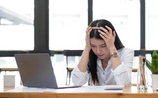 la imagen de una mujer de negocios asiática está estresada, aburrida y pensando demasiado por trabajar en una tableta en la oficina. foto