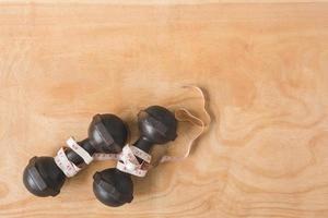 Top view of iron dumbbells with measure tape on wooden table background. Free space for text photo