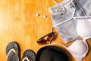 Top view of Summer clothes and accessories for woman on wooden table. Summer Beach Outfit. Vacation concept photo