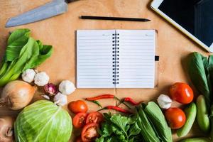 Top view of Fresh vegetables with blank notebook on wooden table background. photo