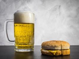 Hamburger with Glass of beer on the table over a grunge background. photo