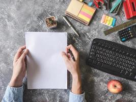 Top view of Male hands holding paper sheet with Office supplies on Grunge gray background photo