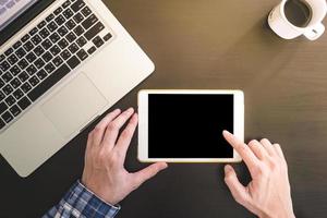 vista superior de manos masculinas usando tableta, computadora portátil con taza de café en el escritorio. foto