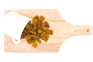 Yellow raisins with cup  on wooden tray. photo
