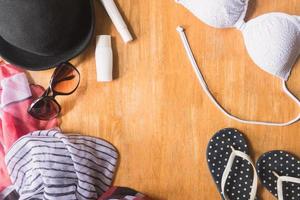 Top view of Summer clothes and accessories for woman on wooden table. Summer Beach Outfit. Vacation concept photo