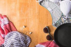 Top view of Summer clothes and accessories for woman on wooden table. Summer Beach Outfit. Vacation concept photo