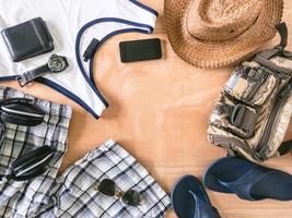 Top view of male summer accessories, clothes and gadgets on the wooden background. photo