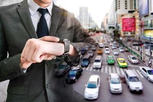 Double exposed of businessman checking time on his wrist watch with traffic jam in the city photo