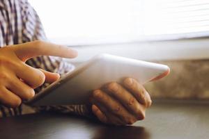 Close up of male hands using Tablet on the desk,toned with sunlight. photo