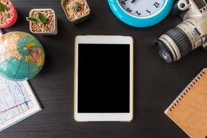 Top view of tablet with camera,cactus,map,globe,clock and notebook on the office desk. photo