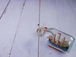 boat in  bottle on wood table for travel or transport concept photo