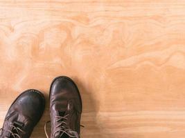 botas de hombre de cuero marrón sobre fondo de mesa de madera, espacio libre para texto foto