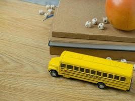 The school bus toy and apple on wood table for back to school or education concept photo