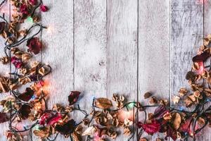 Christmas lights with dry leaves on wooden table photo